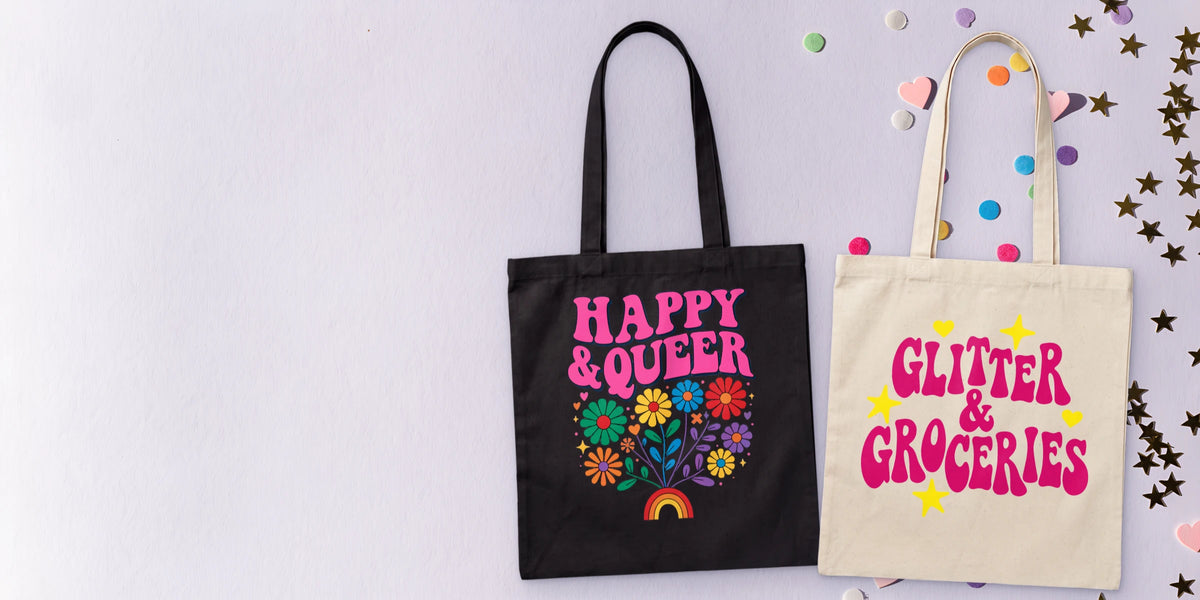 Custom printed tote bags laid flat: black Happy & Queer and natural Glitter & Groceries