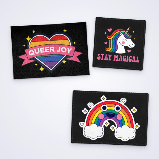 Custom full colour sew-on patches: a Queer Joy rainbow heart, a smiling rainbow and a rainbow unicorn with Stay Magical